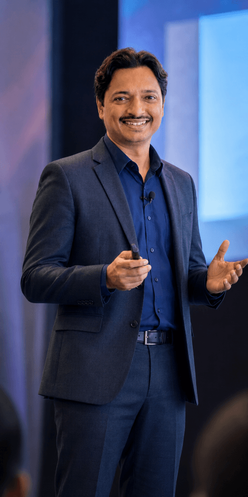 Jaydeep Adesara presenting on stage with a clicker during a technology session