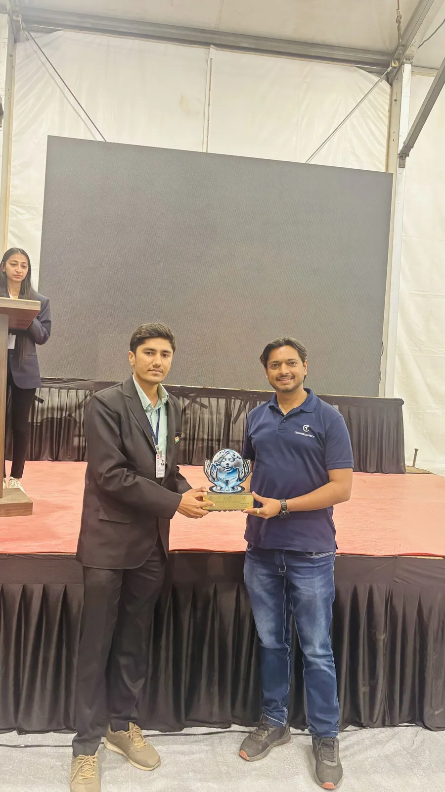 Jaydeep Adesara presenting a student recognition trophy